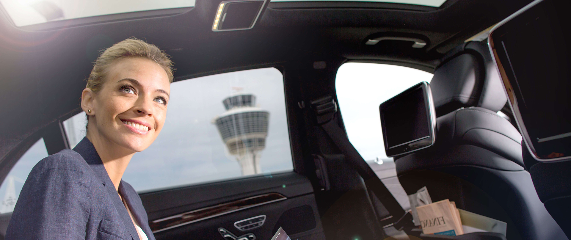 Eine Frau sitzt lächelnd in einer Limousine.